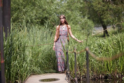 beautiful hippie girl standing on a wooden bridge in the Park