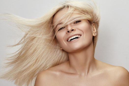 Beautiful woman with magnificent blond hair. Happy model face with windswept flying hair. Shiny long health hairstyle