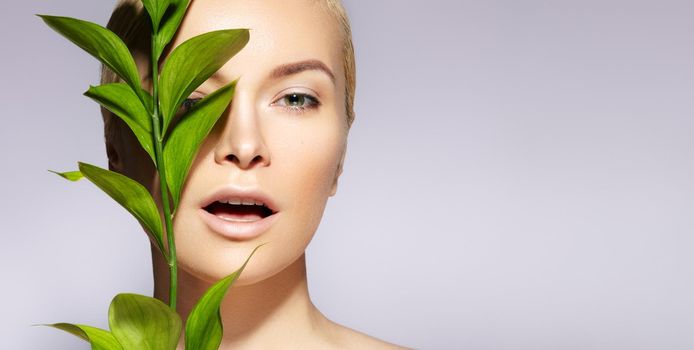 Beautiful woman applies Organic Cosmetic. Spa and Wellness. Model with Clean Skin, Natural Make-Up, leaf. Copy Space