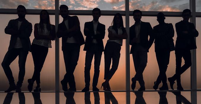 silhouette of a business team standing next to the office window