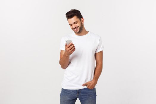 Happy casual man playing on smartphone over gray background