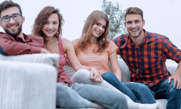 group of cheerful friends sitting on sofa