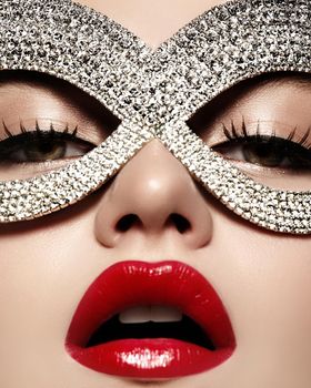 Beautiful Model with Fashion Lips Makeup wearing bright brilliant mask. Masquerade style woman. Holiday celebration look