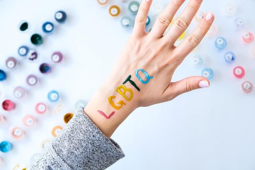 Rainbow LGBTQ flag painted on hand. Support for lgbt community. Honour of pride month. Connecting people, touching hands.