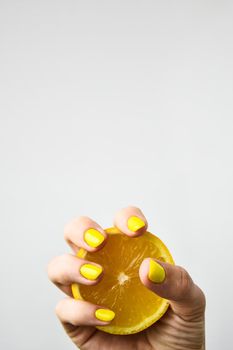 Female hand with stylish colorful yellow nails holding fresh lemon. Female manicure. glamorous beautiful manicure.