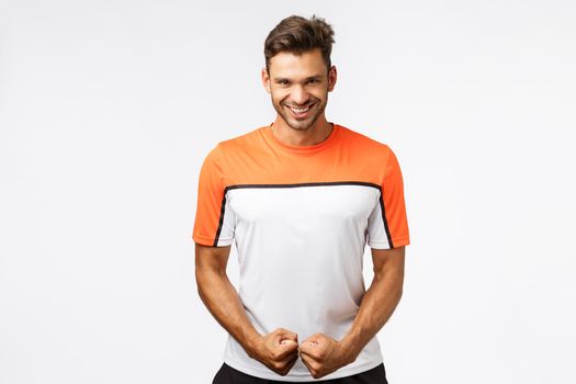 Attractive smiling happy man with bristle, masculine body, smiling assertive and sassy, look satisfied with own strained muscles, feeling powerful and determined, encourage himself before workout