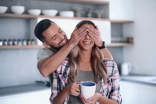happy man joking with his girlfriend in the kitchen in the morning