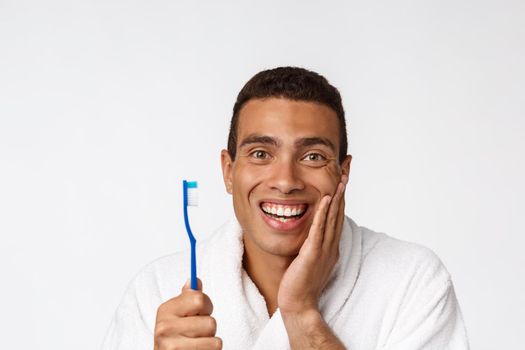 Man with tooth brush. African man holding a toothbrush with tooth brush and smiling while standing over white background.