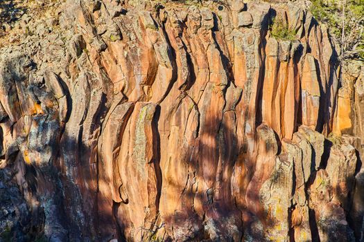 Detail of cliff with wavy vertical rock formations in golden light