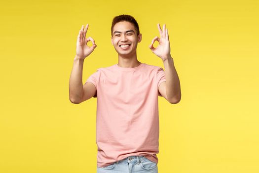 Lifestyle, travel and people concept. Happy cheerful young man, japanese guy showing okay sign and smiling with rejoice and delight, satisfied with quality, guarantee and recommend product