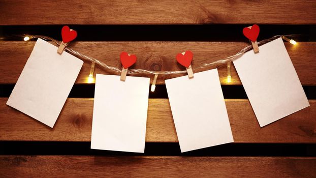 Blank White Stickers hanging on Light Garland with Decorative Love Pins. Cozy Valentines Day Background with Copy Space