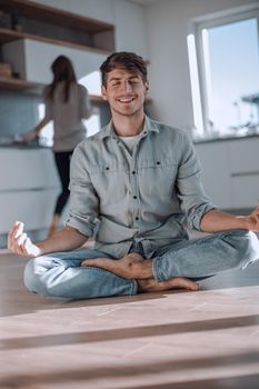 young man sitting in Lotus position on kitchen floor