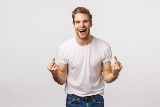 Rude and expressive, intollerant blond happy careless guy, dont care people opinion, fuck-off, showing middle fingers and cursing with smile on face, feeling daring and sassy, white background