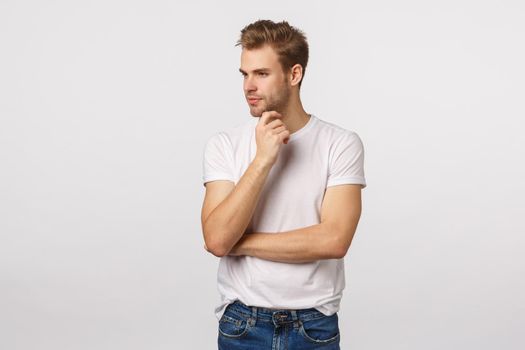 Thoughtful and creative good-looking male manager, designer decide what do, look away thinking, smiling pleased, have interesting idea, concept, standing white background dreamy