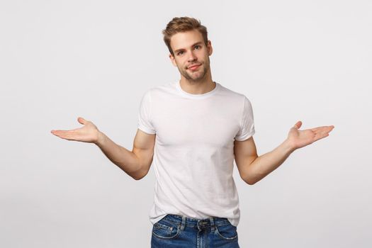 Sorry, I dont know. Careless and tired, unbothered blond young guy, spread hands sideways and shrugging, tilt head as apologizing for failing, making mistake, standing white background