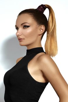 Fashion beautiful young woman with ponytail hairstyle. Pony tail straight hair, catwalk eyeliner makeup on model face