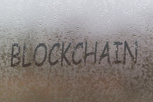 blockchain handwritten on wet glass of night window