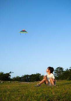 Little girl flying a kite in the field at sunset. Healthy summer activity for children. Funny time with family.