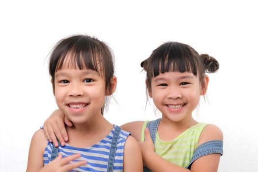 Two little sisters hugging and looking at camera isolated on white background. Two pretty little girls sisters happily cuddle and laugh. friendship and love concept.