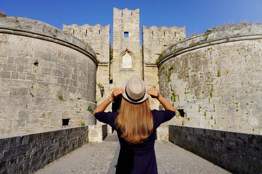 Tourism in Greece. Back view of tourist girl visiting the old Fortifications of Rhodes City, Greece. Unesco world heritage site.