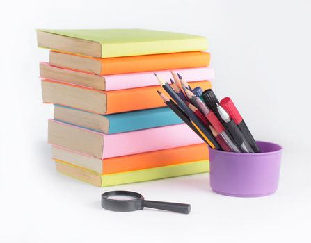 magnifying glass, pencils and stack of books on white background