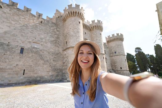 Young woman taking self portrait in front of Palace of the Grand Master of the Knights of Rhodes, Greece