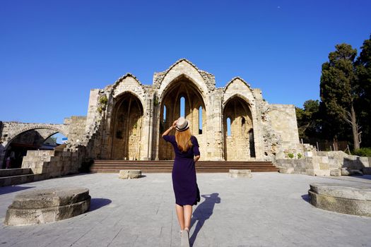 Back view of tourist girl visiting Church of the Virgin of the Burgh, Rhodes, Greece