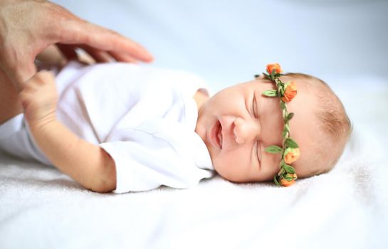 serene newborn baby in the wreath lying on the white sheet