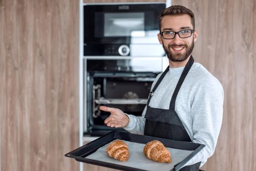 smiling man holding a tray of fresh croissants