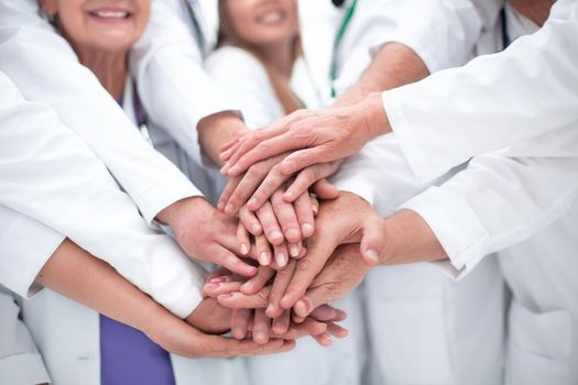 large group of doctors put their hands together.