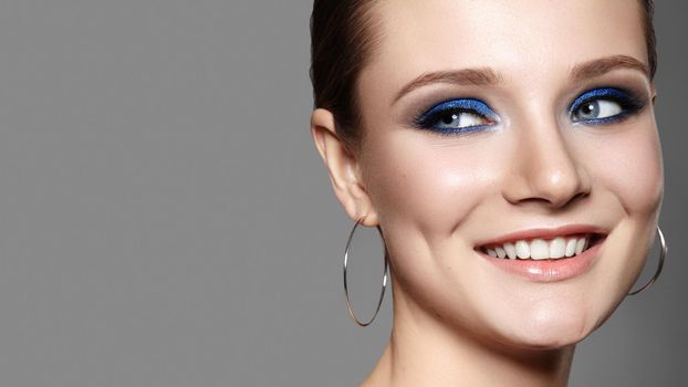 Beautiful Woman with Professional Blue Makeup. Celebrate Style Eye Make-up and Shine Skin. Smiling Fashion Model
