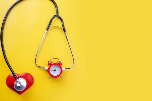 stethoscope  and alarm clock on yellow background. Time to book a  Health Check