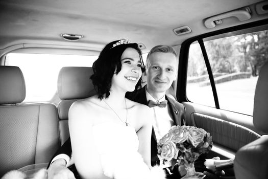 black-and-white photo .the couple sitting in the wedding car.