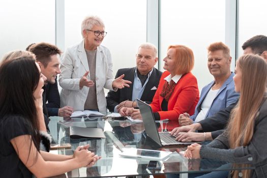 Businesswoman stands to address colleagues around table