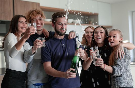 Cheerful young friends opening bottle of champagne