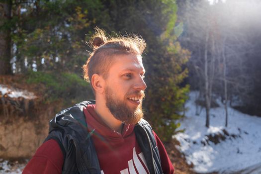 Outdoor portrait of blond bearded smiling hipster man in nature