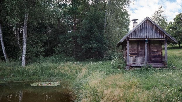 Old and abandoned bathhouse in an overgrown meadow, country forest, Lithuania