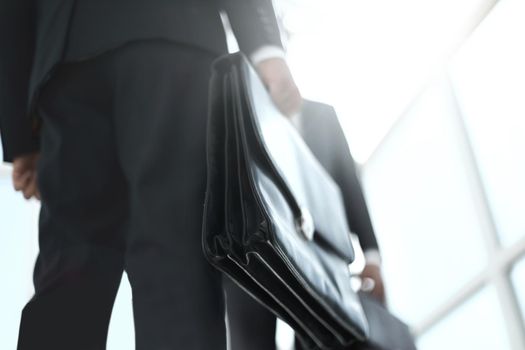 Business men in black suit hand holding briefcase