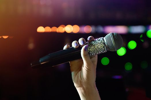 Woman hand holding wireless microphone with rhinestones on stage