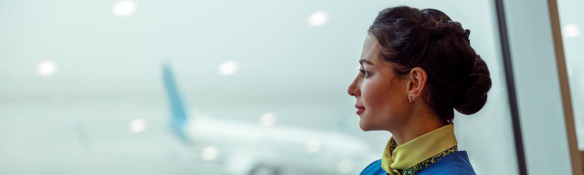 Female flight attendant looking out the window in airport terminal