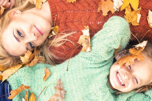 Girl and mom lying on autumn leaves