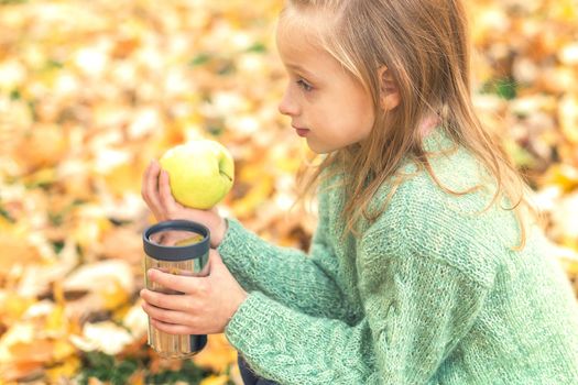 Girl with apple and drink in autumn park