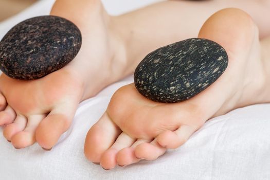 Hot stones lying on female feet