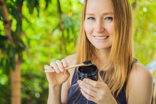 Young woman brush teeth using Activated charcoal powder for brushing and whitening teeth. Bamboo eco brush
