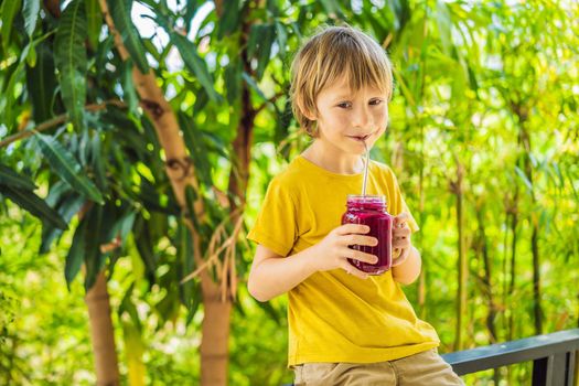 Boy holds smoothies from a dragon fruit with drinking straw