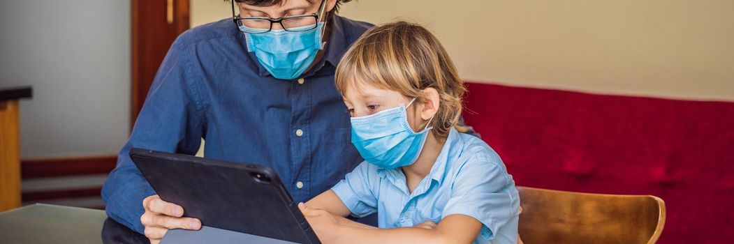 Boy studying online at home using a tablet. Father helps him learn. Father and son in medical masks to protect against coronovirus. Studying during quarantine. Global pandemic covid19 virus BANNER, LONG FORMAT