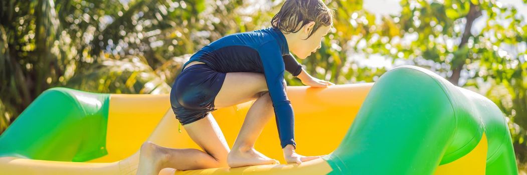 Cute boy runs an inflatable obstacle course in the pool BANNER, LONG FORMAT