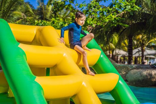 Cute boy runs an inflatable obstacle course in the pool