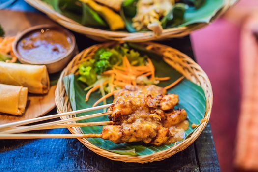 Satay or sate, skewered and grilled meat, served with peanut sauce, cucumber and ketupat. Traditional Malaysian and Indonesian food. Asian cuisine