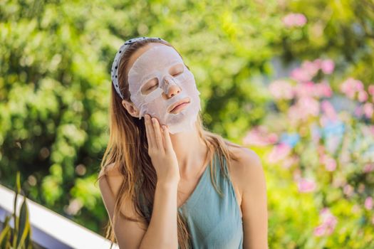 Young red-haired woman doing facial mask sheet. Beauty and Skin Care Concept